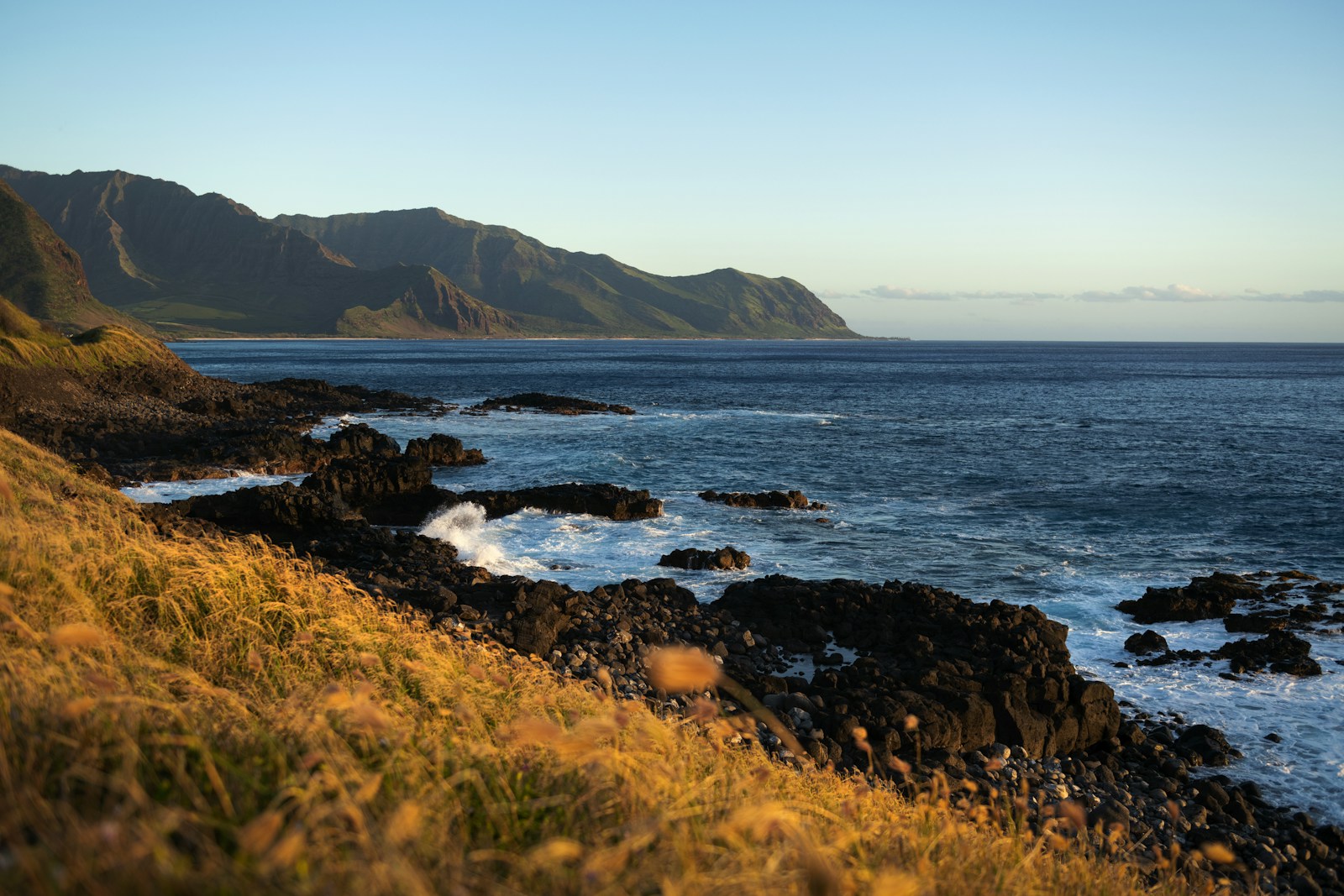 Mountains, blue ocean, and the rocky coastline at Yokohama Bay, Oʻahu.